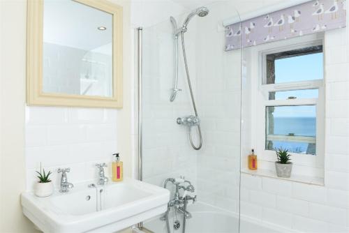 a white bathroom with a shower and a sink at Mousehole Cottage in Penzance