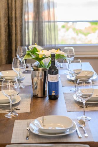 a wooden table with a bottle of wine and glasses at Luxury apartment Barka in Villa with heated pool in Vinišće