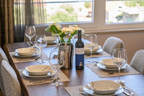 a table with a bottle of wine and glasses at Luxury apartment Barka in Villa with heated pool in Vinišće