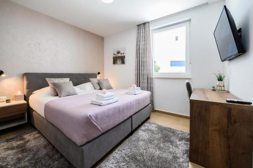 a bedroom with a large bed and a television at Luxury apartment Barka in Villa with heated pool in Vinišće