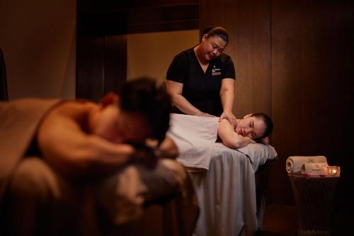a woman standing next to a man laying on a bed at The St. Regis Kuala Lumpur in Kuala Lumpur