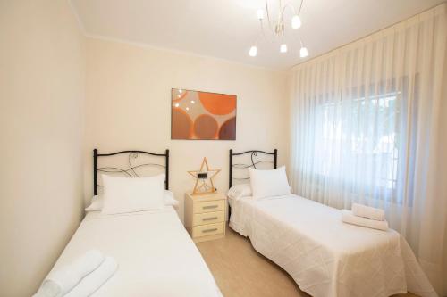 a bedroom with two beds and a window at Chalet Torredembarra Aire Acondicionado zona muy Tranquila in Torredembarra