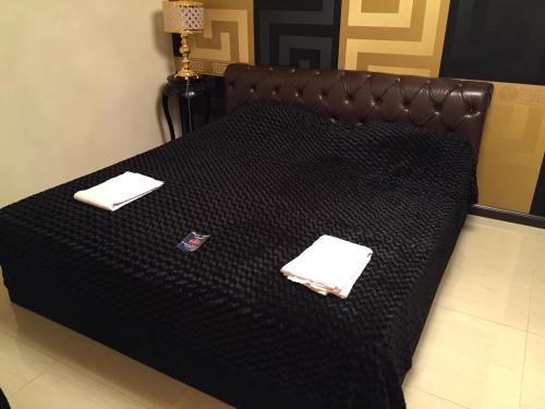 Una cama negra con dos servilletas encima. en Versace Downtown Yerevan, en Ereván