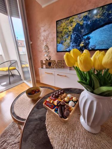 a table with a vase with yellow tulips and a vase with cookies at Apartman M&M in Brčko