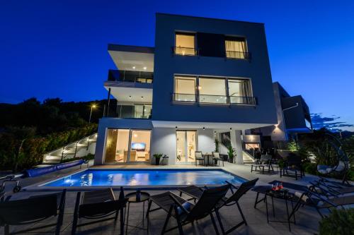a villa with a swimming pool at night at Luxury apartment Barka in Villa with heated pool in Vinišće