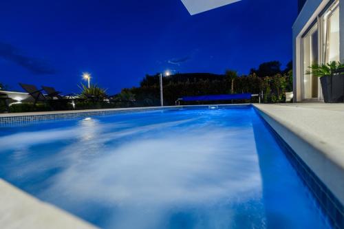 a swimming pool in a house at night at Luxury apartment Barka in Villa with heated pool in Vinišće