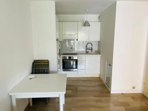 une cuisine avec des armoires blanches et une table blanche dans l'établissement Beach apartment with tropical garden and mountain view Best location, à Menton