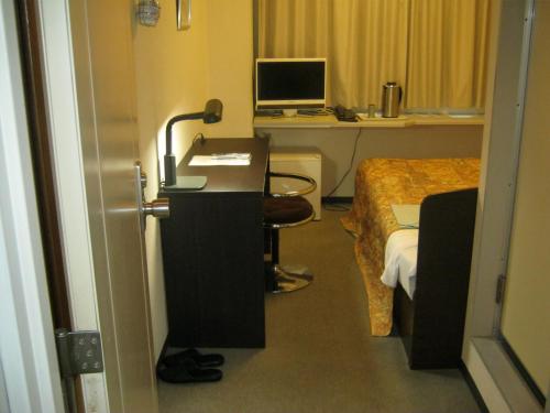 um quarto com uma cama e uma secretária com um computador em Hotel Avanti em Tokushima
