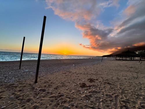 two poles in the sand on a beach at sunset at Heaven Apartment Drimades Olea Residence in Gjilek