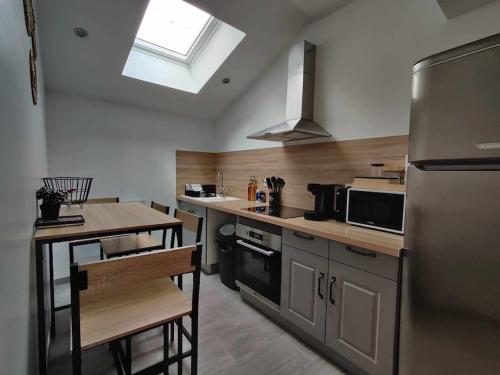 une cuisine avec un réfrigérateur et une table à l'intérieur dans l'établissement La Petite Falaise, maison avec cour Dreux centre, à Dreux