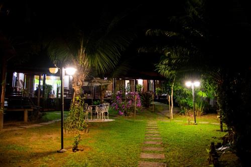 a garden at night with a street light and palm trees at Casa Barra do Sana in Sana