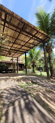 a wooden pergola in a park with palm trees at Casa Barra do Sana in Sana