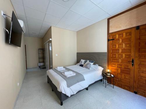 a bedroom with a bed and a wooden door at Júbilus Rooms in Toledo