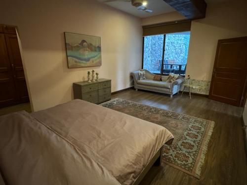 a bedroom with a bed and a couch and a window at 3-BR Murree Hills Hideaway with Scenic View in Murree