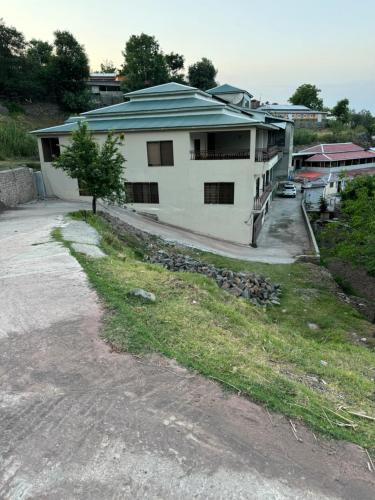 a white house with a tree in front of it at 3-BR Murree Hills Hideaway with Scenic View in Murree