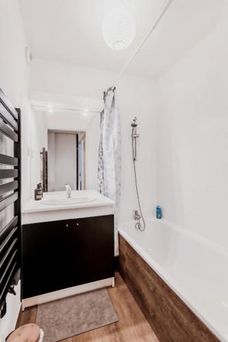 une salle de bain avec un lavabo blanc et une baignoire dans l'établissement Superbe appartement - Parking Gratuit - 4 Personnes, à Chambéry