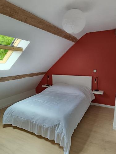 une chambre avec un lit blanc avec un mur rouge dans l'établissement Gîte au milieu des vignes, à Saint-Aignan