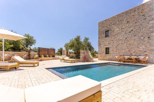 a swimming pool in front of a brick building at Lakkos Villas in Kardamili
