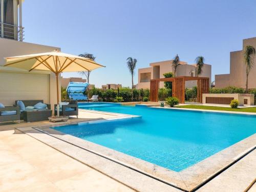 a swimming pool with an umbrella next to a building at Hacienda Bay Villa with private pool in El Alamein