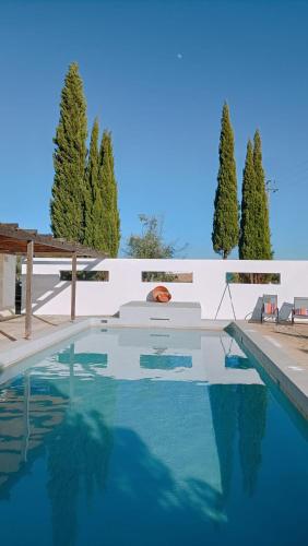 a swimming pool with blue water in front of a white wall at Monte das Oliveiras - Casas de Campo in Estremoz