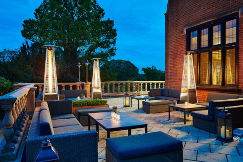a patio with couches and tables on a brick building at Hanbury Manor Marriott Hotel & Country Club in Ware