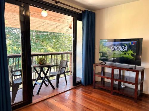 a living room with a television and a table and a balcony at Villa Salento Boutique Apartments & Spa in Salento
