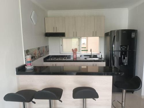 a kitchen with a black refrigerator and black stools at Hermoso apartamento en Girardot in Girardot