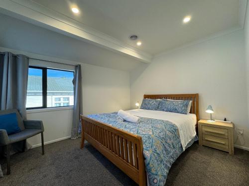 a bedroom with a bed and a chair and a window at NO PARTY ALLOWED, Entire Brand New 3 bedroom townhouse, free unlimited fibre wifi and free parking in Wellington