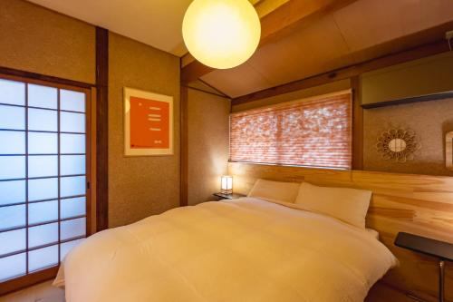 a bedroom with a white bed and a window at Juju Kiseki House in Naoshima