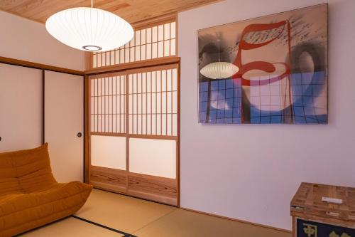 a living room with a chair and a painting on the wall at Juju Kiseki House in Naoshima