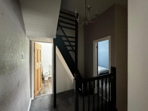 a hallway with a staircase leading to a bathroom with a toilet at Double-Bedroom C4 Manchester Close To Bolton Centre in Little Hulton