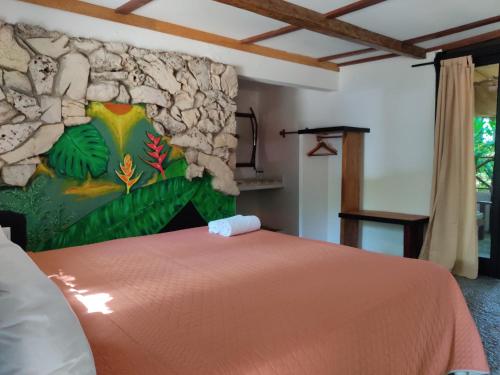 a bedroom with a bed with a stone wall at Hotel Caba&ntilde;as Safari in Palenque
