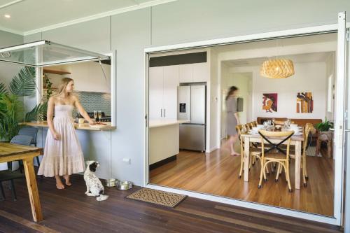 a woman in a dress standing in a living room with a kitchen at Moffat Beach Entertainer with Kids Retreat & Walk to Beach in Caloundra