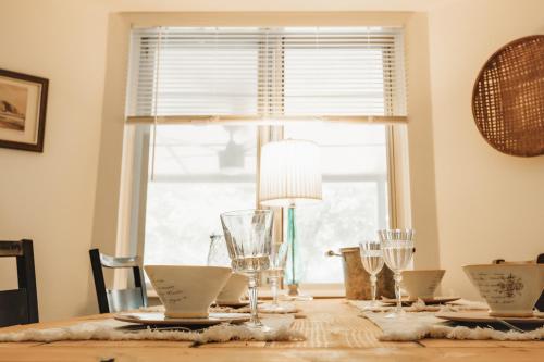 a dining room table with glasses and a window at Wabi Sabi SoCo Retreat- Relax, Work and Soak in the Pool in Austin