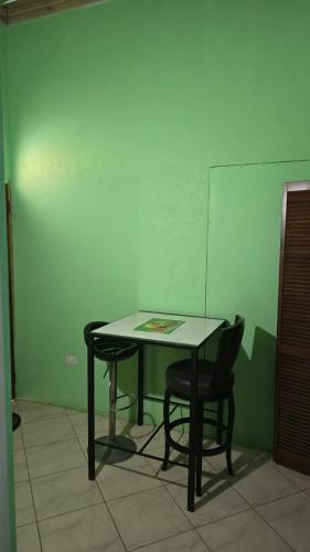a table and chairs in a room with a green wall at Wizzy Apartment White River in Ocho Rios