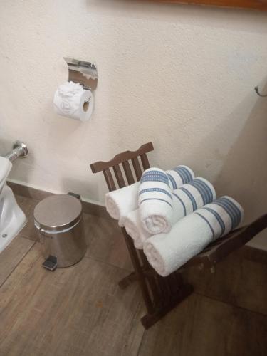 a bathroom with a toilet and towels on a chair at Pousada Casa Jardim in Serra Negra