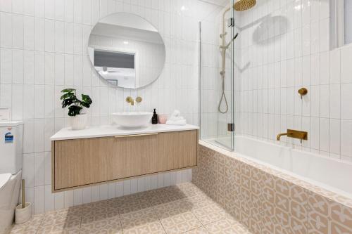 een badkamer met een wastafel, een bad en een spiegel bij A Vue De Rye in Rye