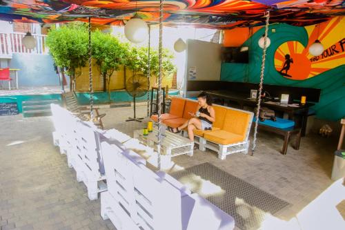 a woman sitting on a swing in front of a pool at Hangover Hostels Mirissa in Mirissa