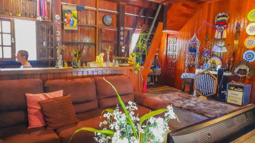 a living room with a brown leather couch and a man at Floresta Zen - Pousada Xamanica in Manaus