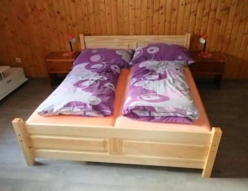 a bed with purple and white pillows on it at Chalupa Iveta in Oščadnica