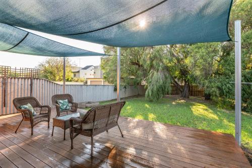 a patio with chairs and a table under a blue umbrella at Seaside Getaway in Dunsborough