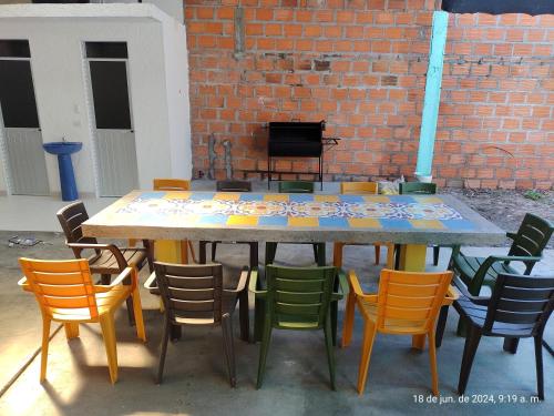 a table with colorful chairs and a brick wall at Casa Valentina habitación#2 para 6 personas in Guamo