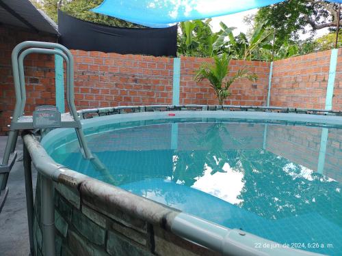 a large swimming pool with a brick wall and an umbrella at Casa Valentina habitación#2 para 6 personas in Guamo