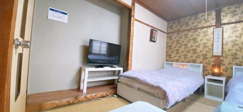 a small bedroom with a bed and a television at Ryokan Sansui in Furano