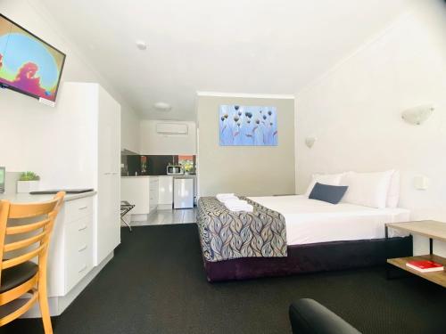 a hotel room with a bed and a desk at Bundaberg Spanish Motor Inn in Bundaberg
