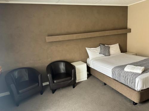 a hotel room with two chairs and a bed at Mid City Plantation Motel in Mildura