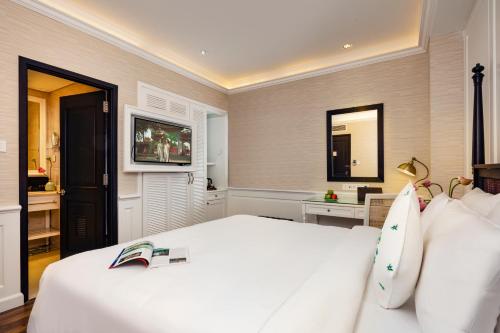 a bedroom with a white bed and a television at Alagon D'antique Hotel & Spa - Wellness Treatment Included in Ho Chi Minh City