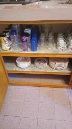 a shelf with plates and cups and bottles on it at Casa Guadalupe Victoria in Matamoros