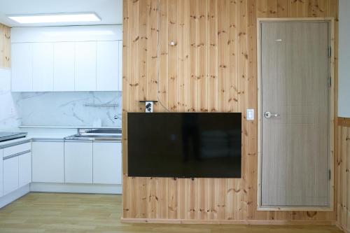 a kitchen with white cabinets and a flat screen tv at Ronnie Pension in Taean