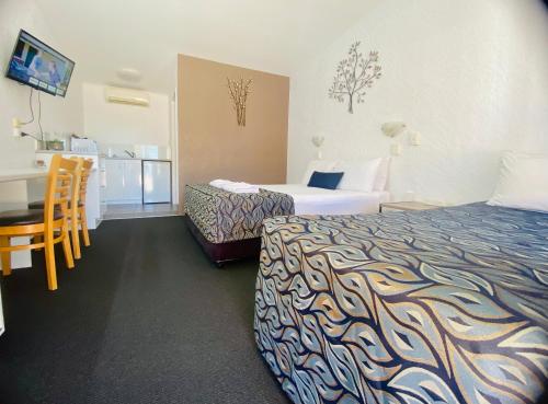 a hotel room with two beds and a table at Bundaberg Spanish Motor Inn in Bundaberg
